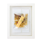 Framed artwork with a yellow leaf and dried flowers on a white background