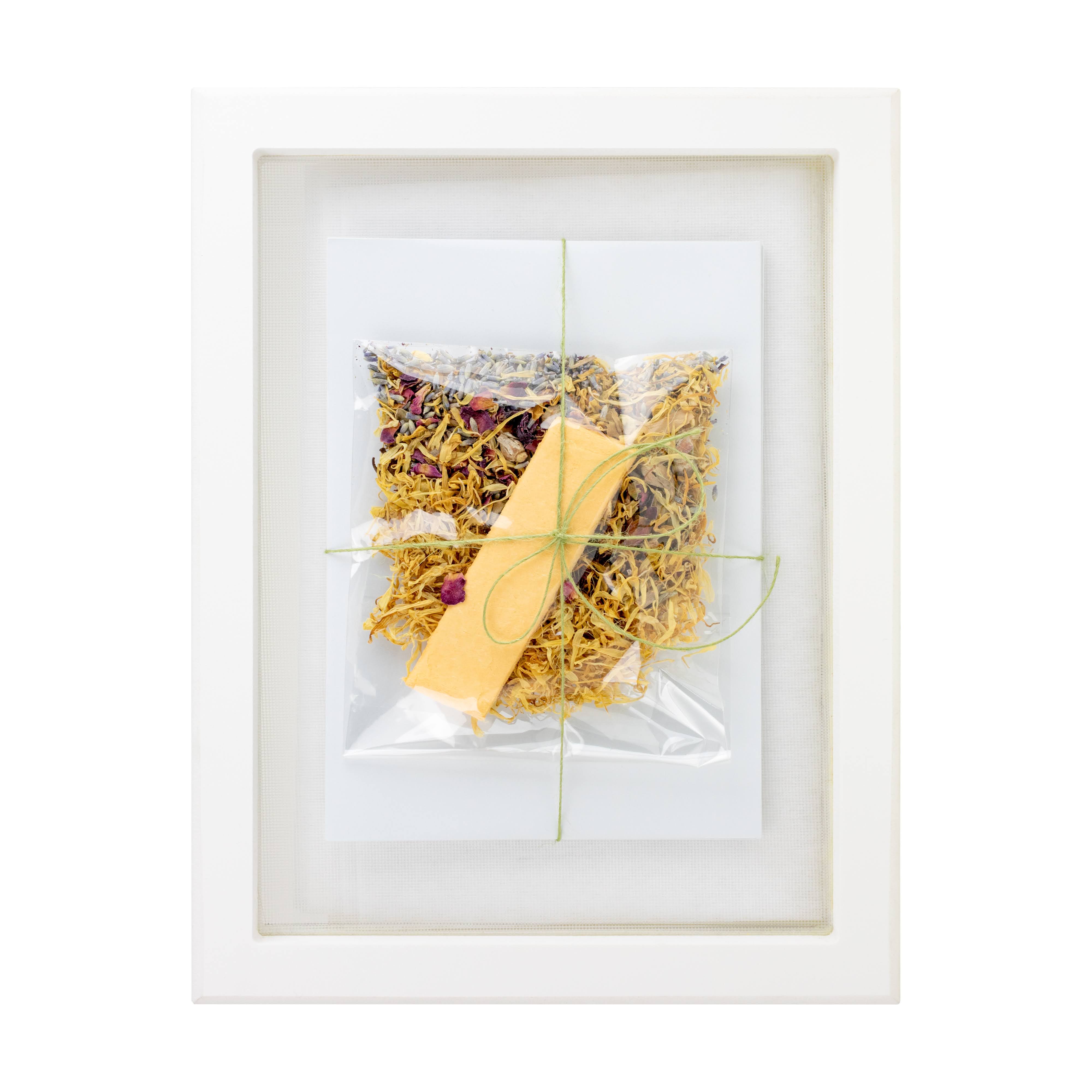 Framed artwork with a yellow leaf and dried flowers on a white background